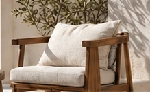A sunlit home with a linen armchair and olive branches